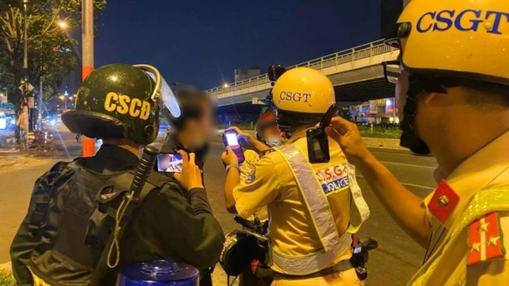 Hình ảnh một cảnh sát giao thông đang dừng một chiếc xe máy trên đường để kiểm tra nồng độ cồn