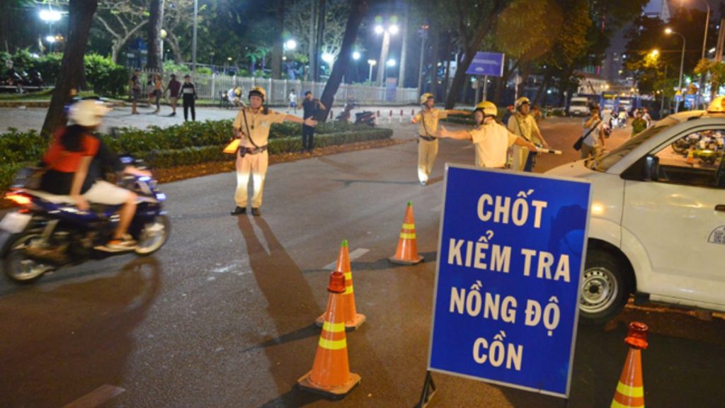 Cảnh sát giao thông đang yêu cầu tài xế xe ô tô thổi vào máy đo nồng độ cồn